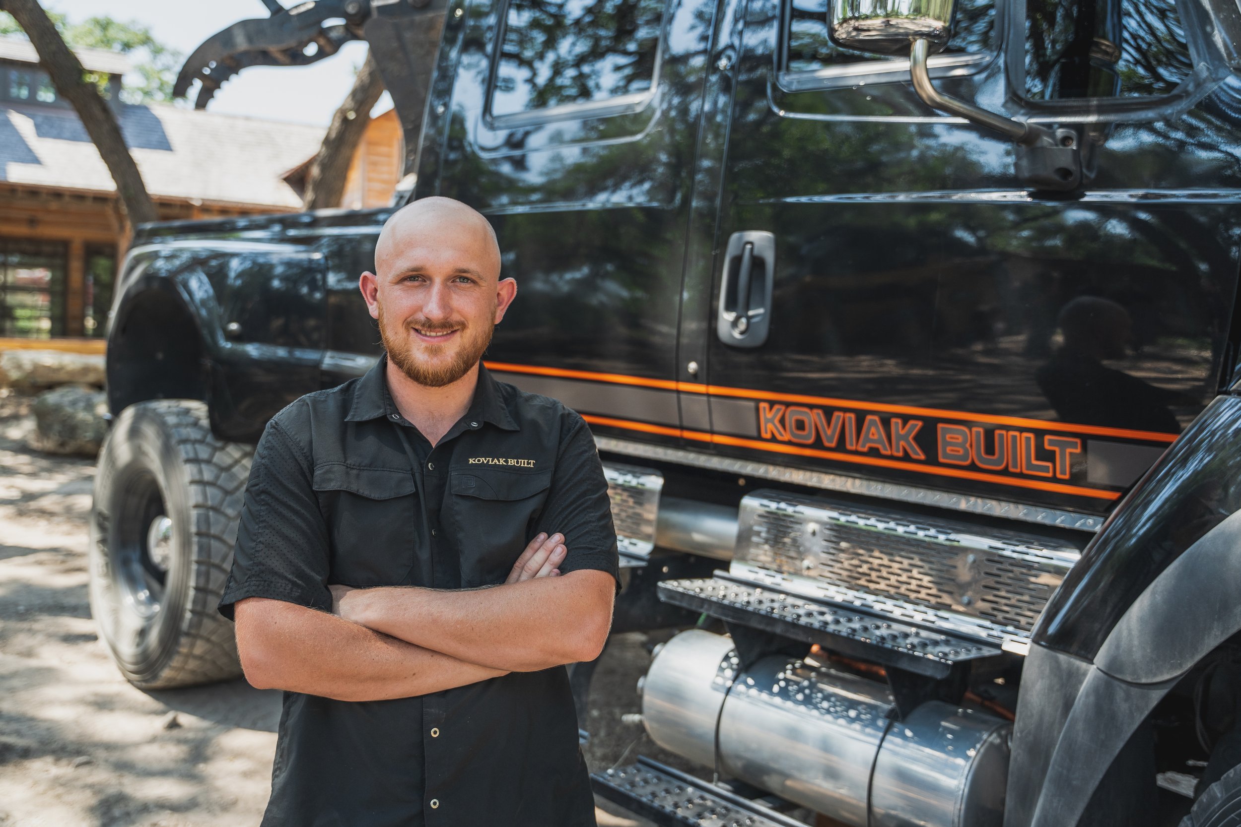 Photo of Caleb pistone standing in front of a large truck wearing a black koviak built shirt