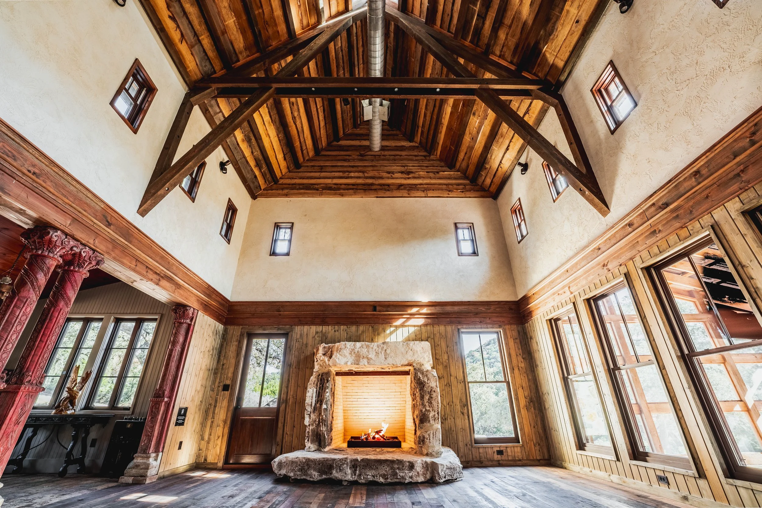 H2 Lodge stone fireplace beneath a wood beam ceiling